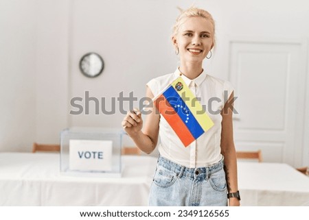 Young blonde woman holding venezuela flag smiling at electoral college