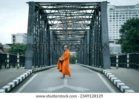 Buddhist monks are morning walking on routes between rural villages on the ancient iron bridge the travel destination of Chiang Mai, Thailand. Concepts make merit with monks in culture and religion. Royalty-Free Stock Photo #2349128129