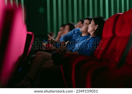 Happy couple watching movie on vacation in big cinema
