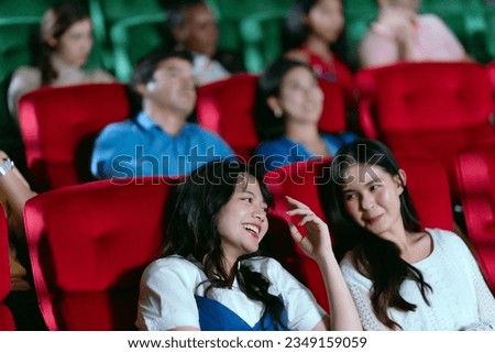 Young happy lesbian couple watching movie on vacation in big cinema