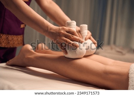 Qualified spa therapist giving hot compress leg massage to patient