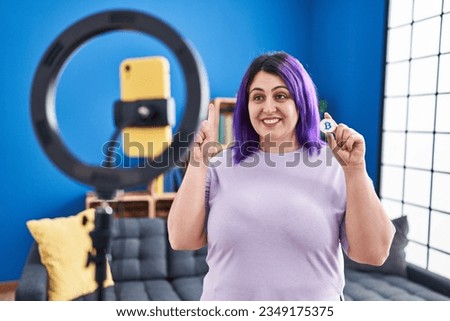 Plus size woman wit purple hair recording bitcoin tutorial with smartphone at home smiling with an idea or question pointing finger with happy face, number one 