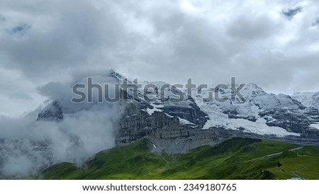 Snowy mountains in the Swiss Alps, Grindenwald, Switzerland. Grey rocky mountains a cloudy day.
