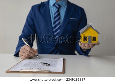 Real estate agent holding house model, insurance salesman handing over the model home to client after signing sale, successful sale at office close up pictures