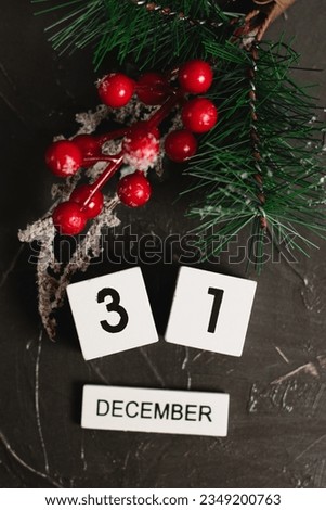 Flatlay, wooden calendar with the date December 31 and Christmas decoration on a dark textured background