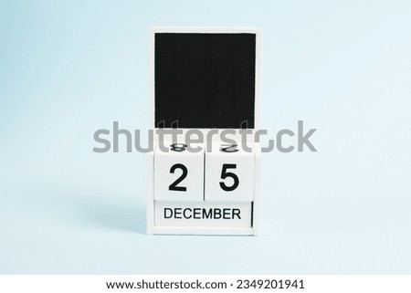 Christmas, wooden calendar with the date December 25 on a blue background with copy space. The concept of preparing for the celebration of Christmas and New Year and plans for the future