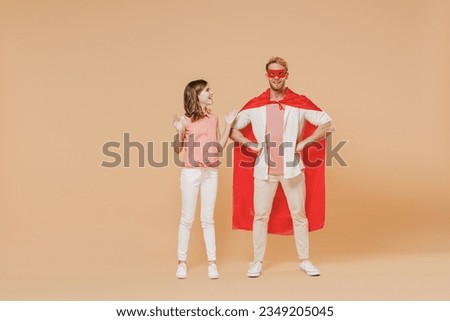 Full length smiling cool powerful man stand akimbo in superhero suit, have supernatural abilities, enjoy free time together with kid teen daughter isolated on beige background. Real heroes defend you.