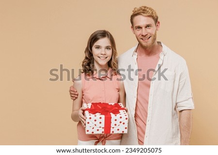 Young happy parent man with child teen girl in casual pastel clothes Daddy little kid daughter red present box with gift ribbon bow isolated on beige background. Father's Day Love birthday concept.