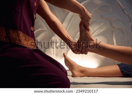 Wellness center masseuse giving Thai feet massage to woman