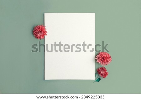 Blank paper sheet with decorations on pastel green background. Greeting card, invitation mockup. Place for inscription. Pumpkin, autumn flower. Modern Minimal business mock up, template. Top view note