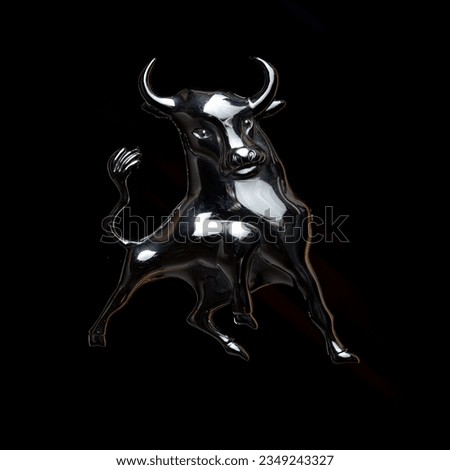 Chromed bull with large horns on a black background. The tail is raised high

