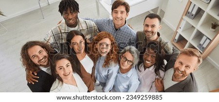 Happy diverse business team at work in office. Top view high angle shot from above group portrait of young and senior multiracial multiethnic people standing together, looking up at camera and smiling Royalty-Free Stock Photo #2349259885