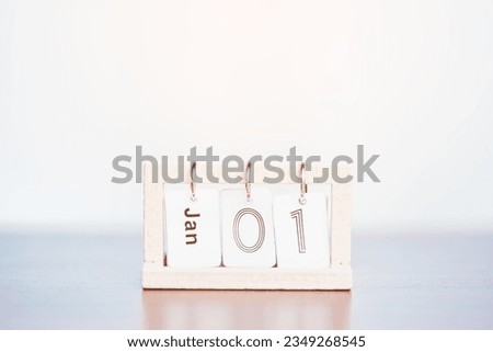A calendar showcasing the date of January 1st is on a wooden table with a soft and gentle orange sunlight from the outside for the concept of New Year festival.