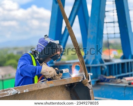 welder in blue suit Wearing a welding mask, welding steel at a construction site Royalty-Free Stock Photo #2349278035