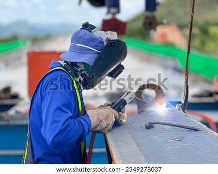 welder in blue suit Wearing a welding mask, welding steel at a construction site Royalty-Free Stock Photo #2349278037