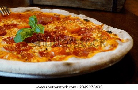 a delicious traditional Italian pizza on a plate on the wooden table made of dark wood at an Italian restaurant                               