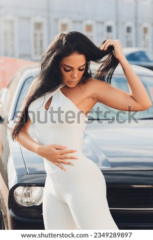 beautiful sports girl in a white bodysuit on a background of a car