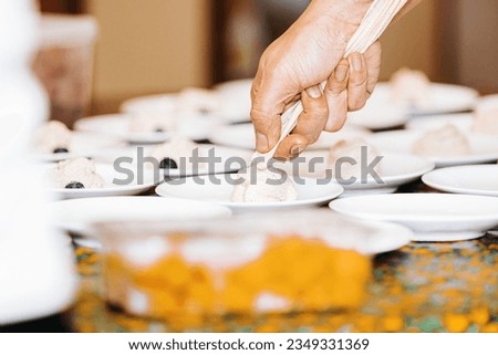 A picture of a hand using a pipe bag to fill the dessert pieces on a table. Chef in action, tasty food. One person, horizontal image.