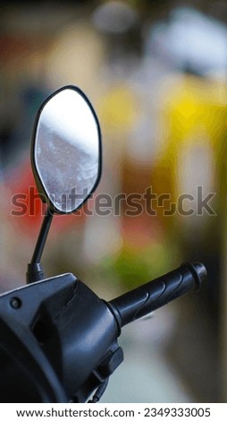 A photo focusing on the rearview mirror of a motorcycle against the background of a colorful wall blur