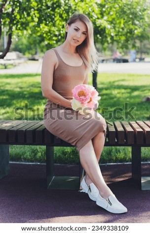 attractive woman sits o bouquet of peony flowers