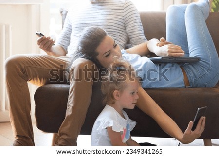 The little girl giggles as she watches cartoons on the smartphone with her parents