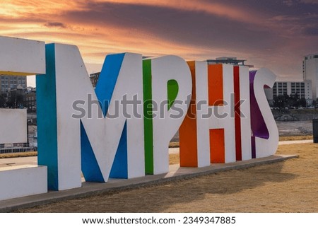 Memphis, Tennessee USA - 11 11 2021: shot of the colorful Memphis sign with skyscrapers and office buildings in the city skyline with yellow grass, blue sky and clouds in Memphis Tennessee USA
