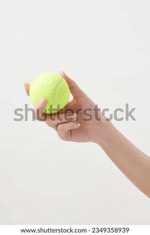 Hand of a woman holding a tennis ball separated from a white background. High definition studio shooting