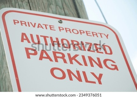 private property authorized parking only sign, red writing on white background with sky background, shot on angle