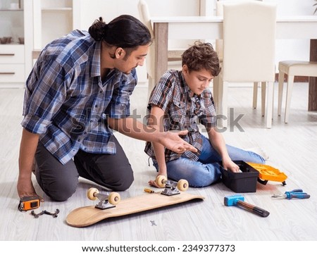 Young father repairing skateboard with his son at home