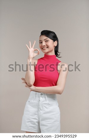 Young asian woman isolated on beige background cheerful and confident showing ok gesture.