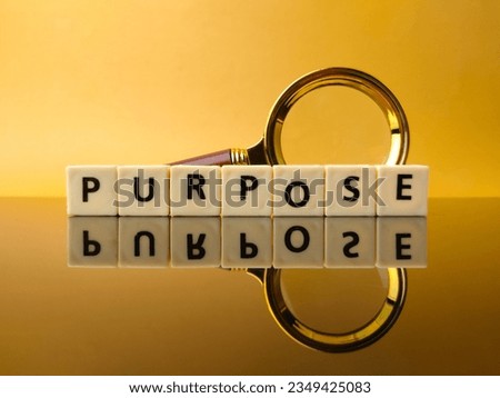 Toys word and magnifying glass with text PURPOSE on yellow background with reflection on a black acrylic board