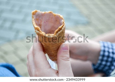 Ice cream cone in hand pastel gray background. . Concept of eating ice cream. A man holds a waffle without ice cream in his hand on a different light background. High quality photo
