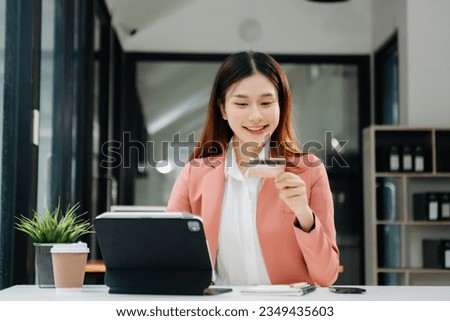 Asian Woman using smart phone for mobile payments online shopping, omni channel, sitting on table, virtual icons graphics interface screen 
