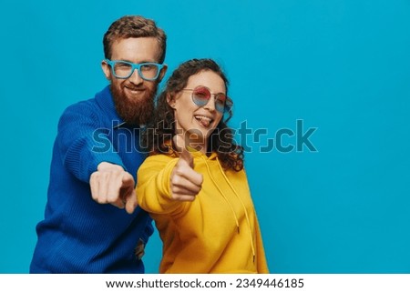 A woman and a man fun couple cranking and showing signs with their hands smiling cheerfully, on a blue background, The concept of a real relationship in a family.