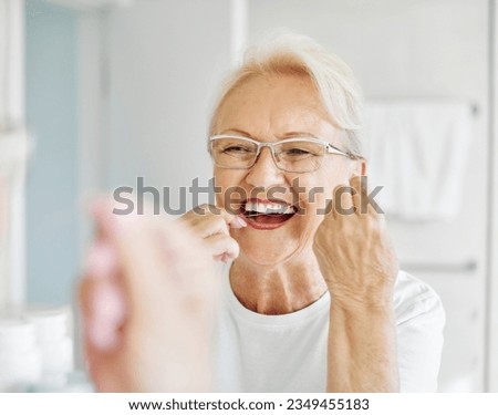 Portrait of an elderly senior woman is cleaning brushing his teeth using dental floss in front of mirror in bathroom. Dental hygiene, vitality and beauty concepts Royalty-Free Stock Photo #2349455183