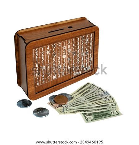 Wooden piggy bank with 500 euro target on white background. There are coins and paper money in front of the piggy bank. Still life concept product shoot stock photo.