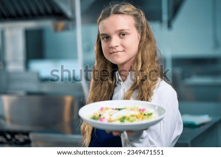 Smiling yong chef girl present a dish of sunny egg salad in real kitchen for meal after completed cook. Royalty-Free Stock Photo #2349471551