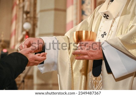 The priest gives the sacramental bread to the faithful during the mass. Catholic priest giving the Communion bread in cathedral.  Royalty-Free Stock Photo #2349487367
