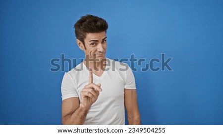 Young hispanic man saying no with finger smiling over isolated blue background Royalty-Free Stock Photo #2349504255