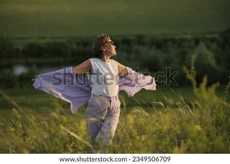 smiling Asian woman of older age in a summer park, holding wild flowers. The video conveys an atmosphere of enjoying nature and tranquility Royalty-Free Stock Photo #2349506709
