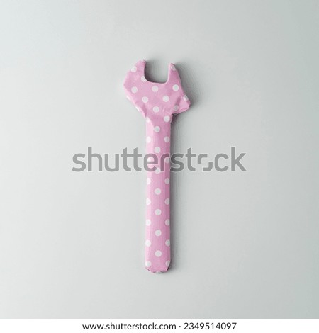 Wrench wrapped in pink polka dot gift paper on blue background. Top view.   Royalty-Free Stock Photo #2349514097
