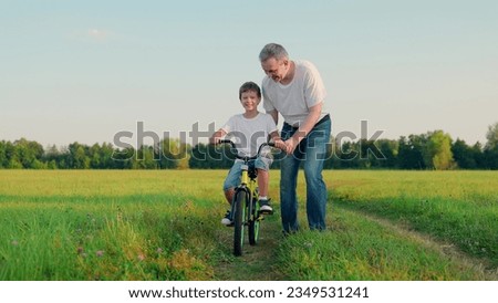 Father teaches his son child to ride bicycle in park. Child is learning to ride bike. Happy family, son dad. Child rides bicycle for first time. Boy kid dream of traveling by bike. Dad helps child.