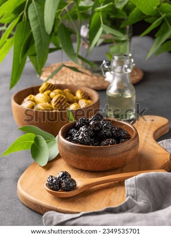 A set of green and black dried olives in bowls on a wooden cutting board on a dark background with olive oil and eucalyptus branch. The concept of vegetarian healthy snacks. Royalty-Free Stock Photo #2349535701