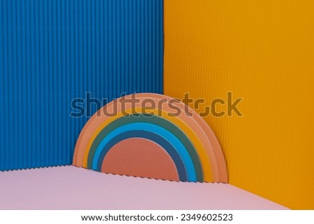 Multicolored rainbow figure on blue yellow background. Multicolored paper rainbow on multicolored background in vintage faded colors. Retro banner in the style of 1960-1970s. Gay, pride month concept. Royalty-Free Stock Photo #2349602523