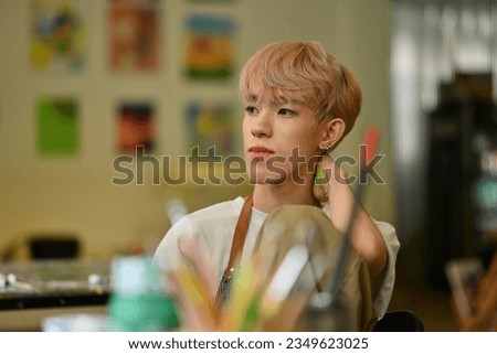 Portrait of an attractive and unique young LGBT artist with colored hair posing playfully in a studio workshop. Royalty-Free Stock Photo #2349623025