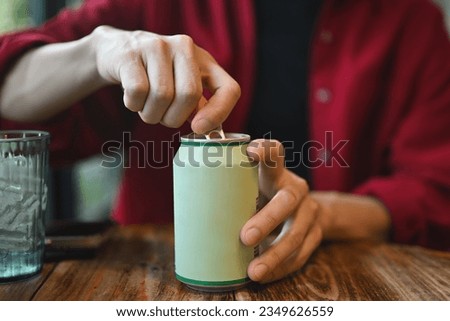 Close up with a Young Asian man's hands opening a drinking can while sitting at the wooden table. Royalty-Free Stock Photo #2349626559