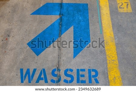 Blue arrow and the word water painted on concrete floor.