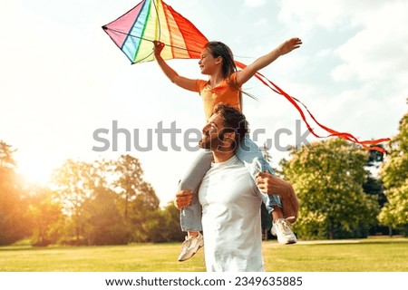 Happy young father playing with his beloved daughter with an air colorful kite in a meadow in the park, having fun together on a warm sunny weekend. Royalty-Free Stock Photo #2349635885