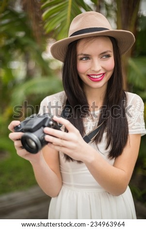Pretty brunette holding her camera outside in the garden