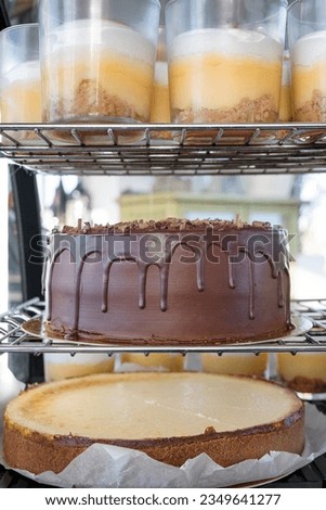 Dessert display fridge filled with some decadent sweet treats such as cheesecake, chocolate cake and lemon custard cups, various confectionery stored in a cooling environment at a restaurant or bakery